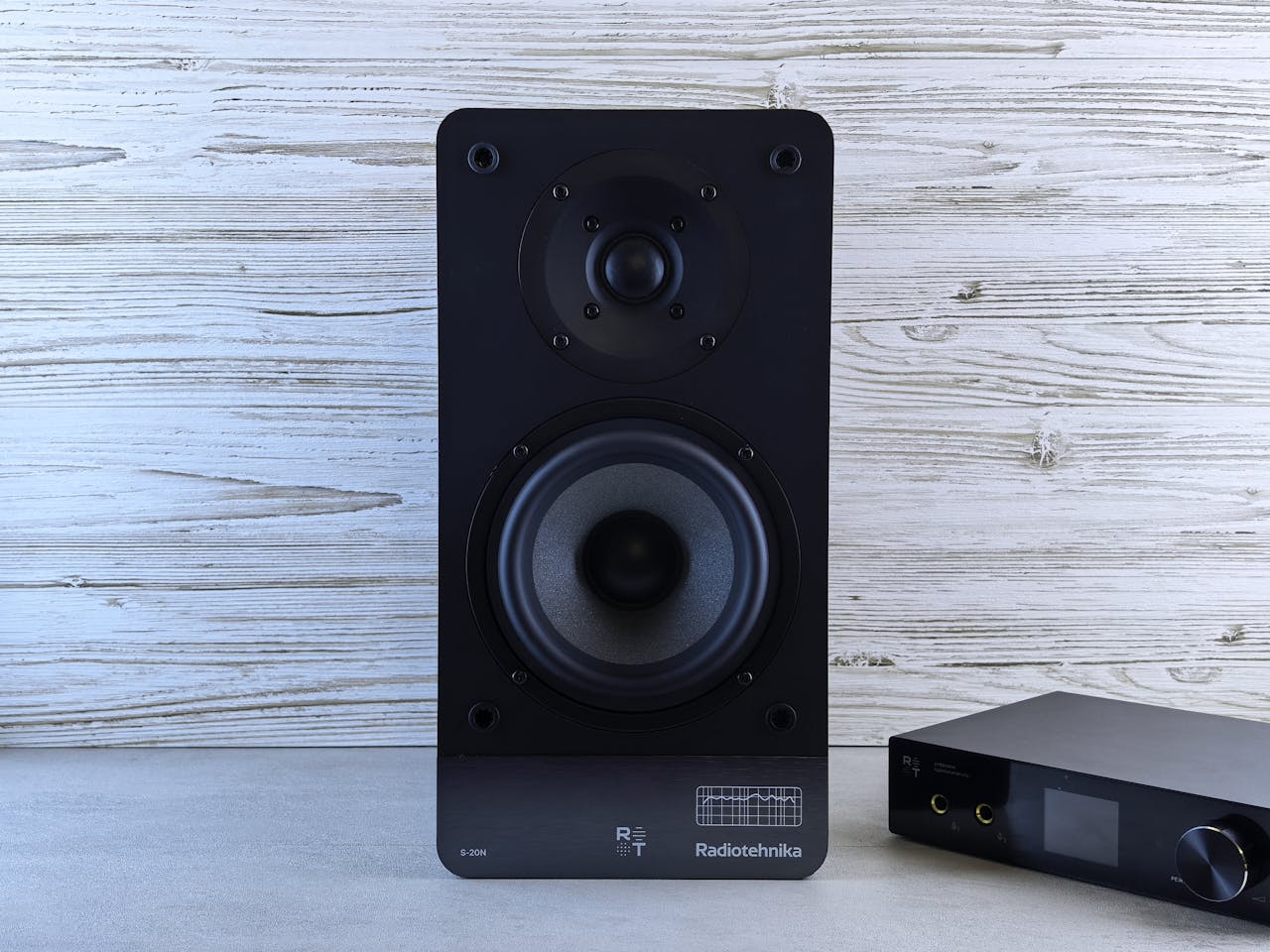 High-quality black loudspeaker and amplifier on a wood background, perfect for audio setups.